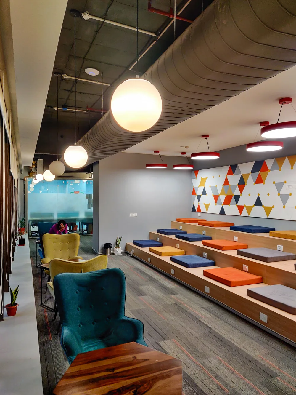 Shared lounge area with colourful seating, tiered benches and pendant lights