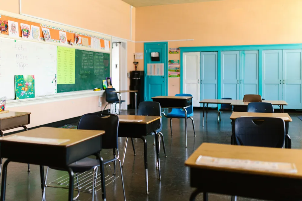 Empty classroom with desks, chairs and a chalkboard