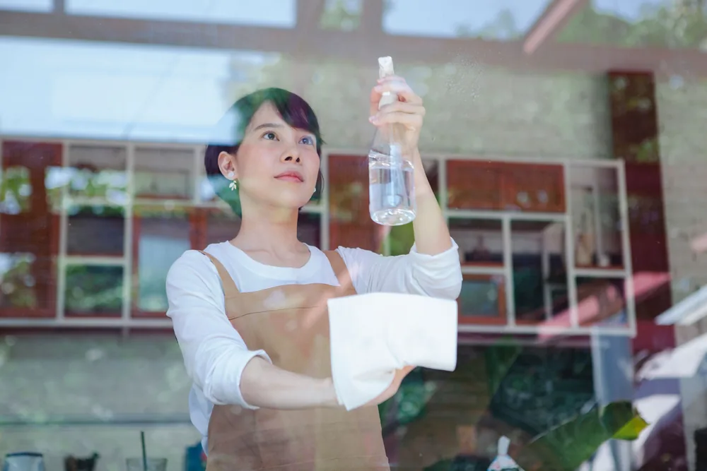 Cleaner spraying and wiping a large shop window